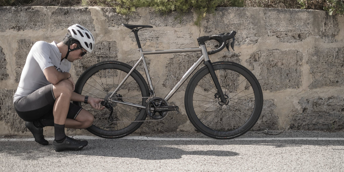 Titanium road bike against a stone wall in Spain, evoking Jaime's hometown of Burgos