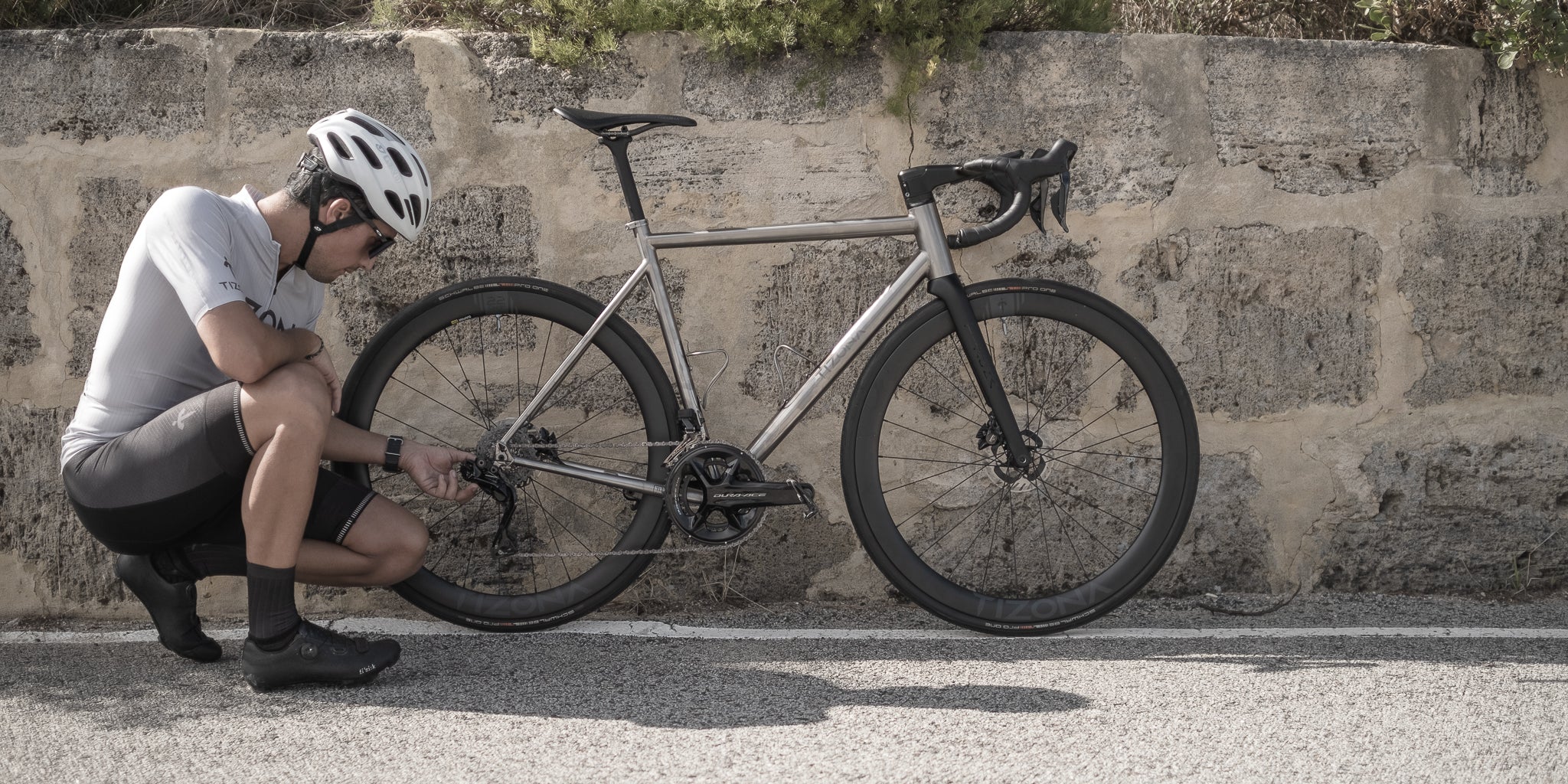 Titanium road bike against a stone wall in Spain, evoking Jaime's hometown of Burgos